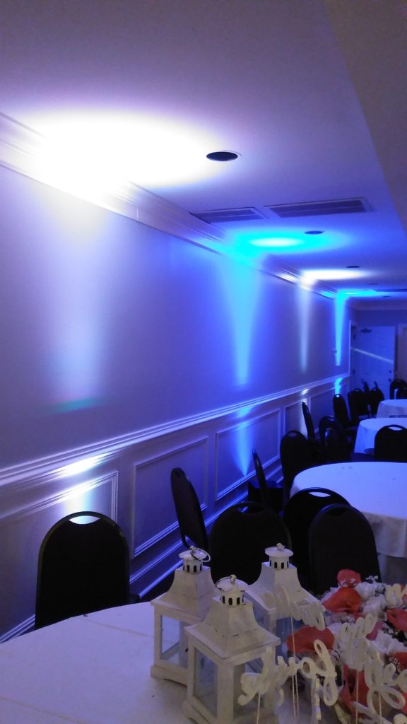 Tables and chairs with blue and white uplights shining on the walls and ceiling